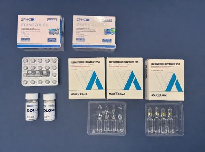 Eine Sammlung von Dopingmitteln, darunter Boxen, Tablettenblister und Ampullen, auf einem Tisch arrangiert.