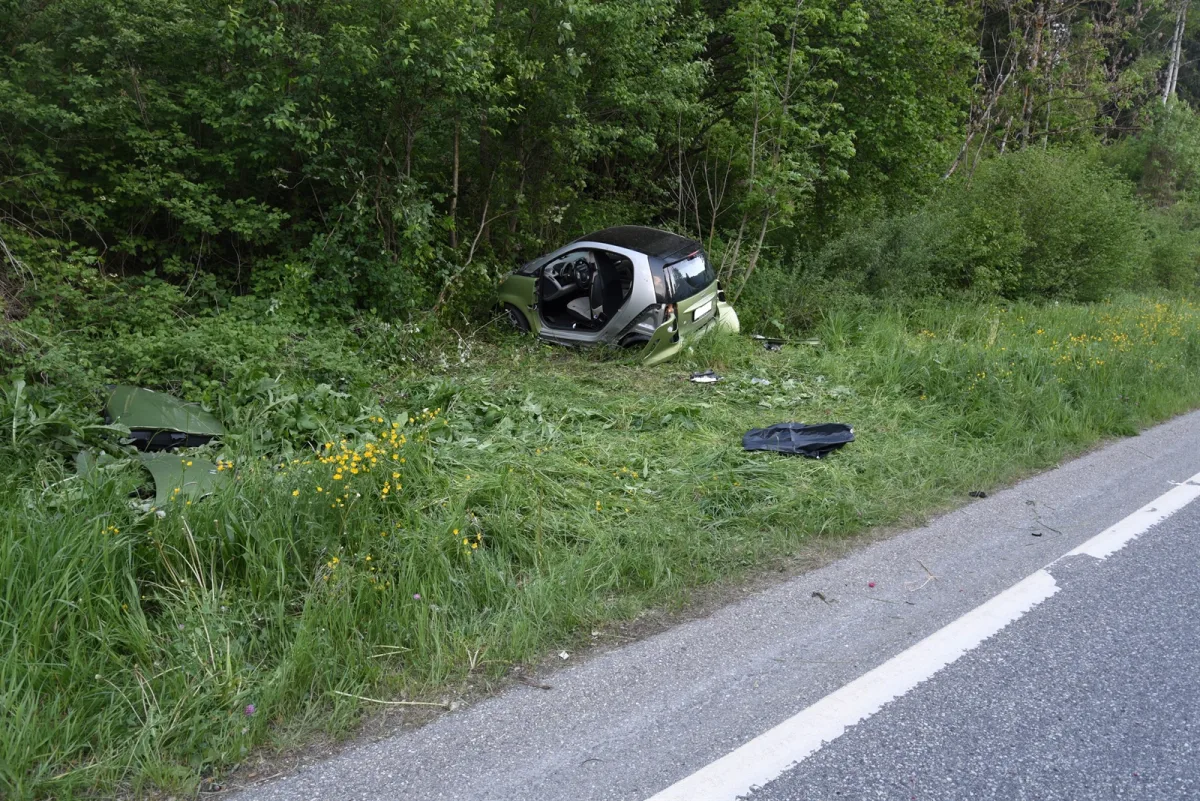 Ein grünes Auto liegt im Graben neben einer Landstraße. Das Fahrzeug ist beschädigt, aber es sind keine Personen sichtbar.