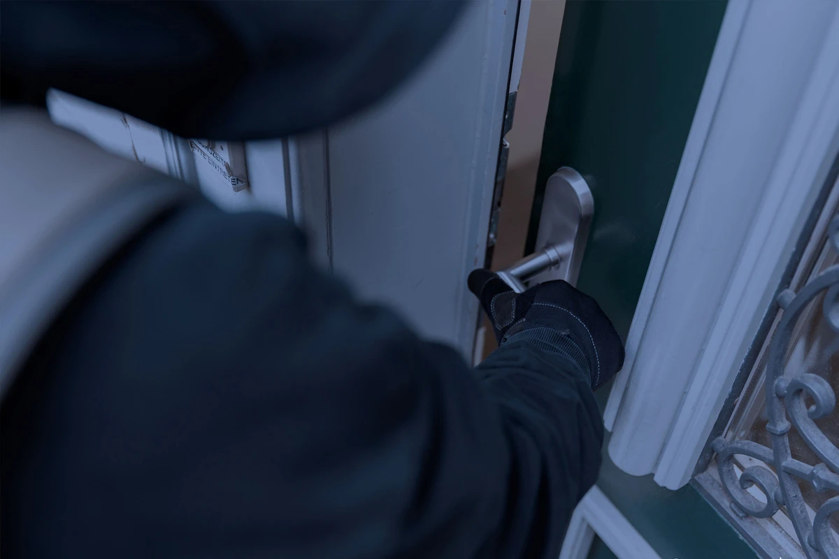 Eine Person in dunkler Kleidung öffnet mit Handschuhen eine Tür. Der Fokus liegt auf der Hand und dem Türgriff.