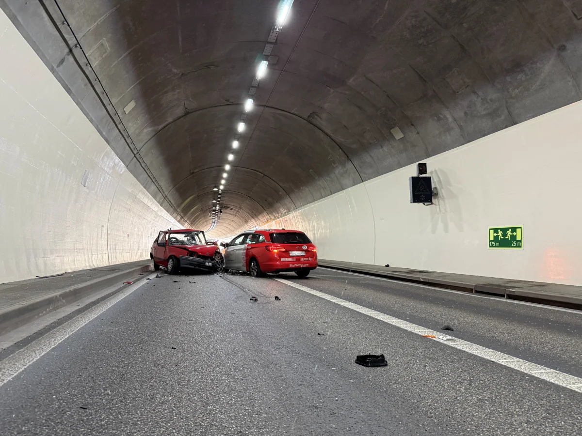 Zwei Autos sind in einem Tunnel frontal kollidiert. Beide Fahrzeuge sind stark beschädigt und Trümmer liegen auf der Fahrbahn.