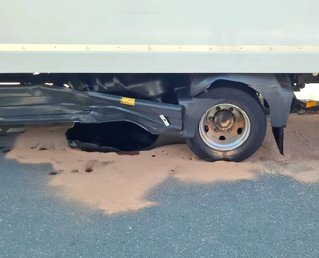 Ein Lastwagen mit beschädigtem Hinterrad, aus dem Flüssigkeit auf die Straße austritt. Der Hintergrund ist nicht erkennbar.