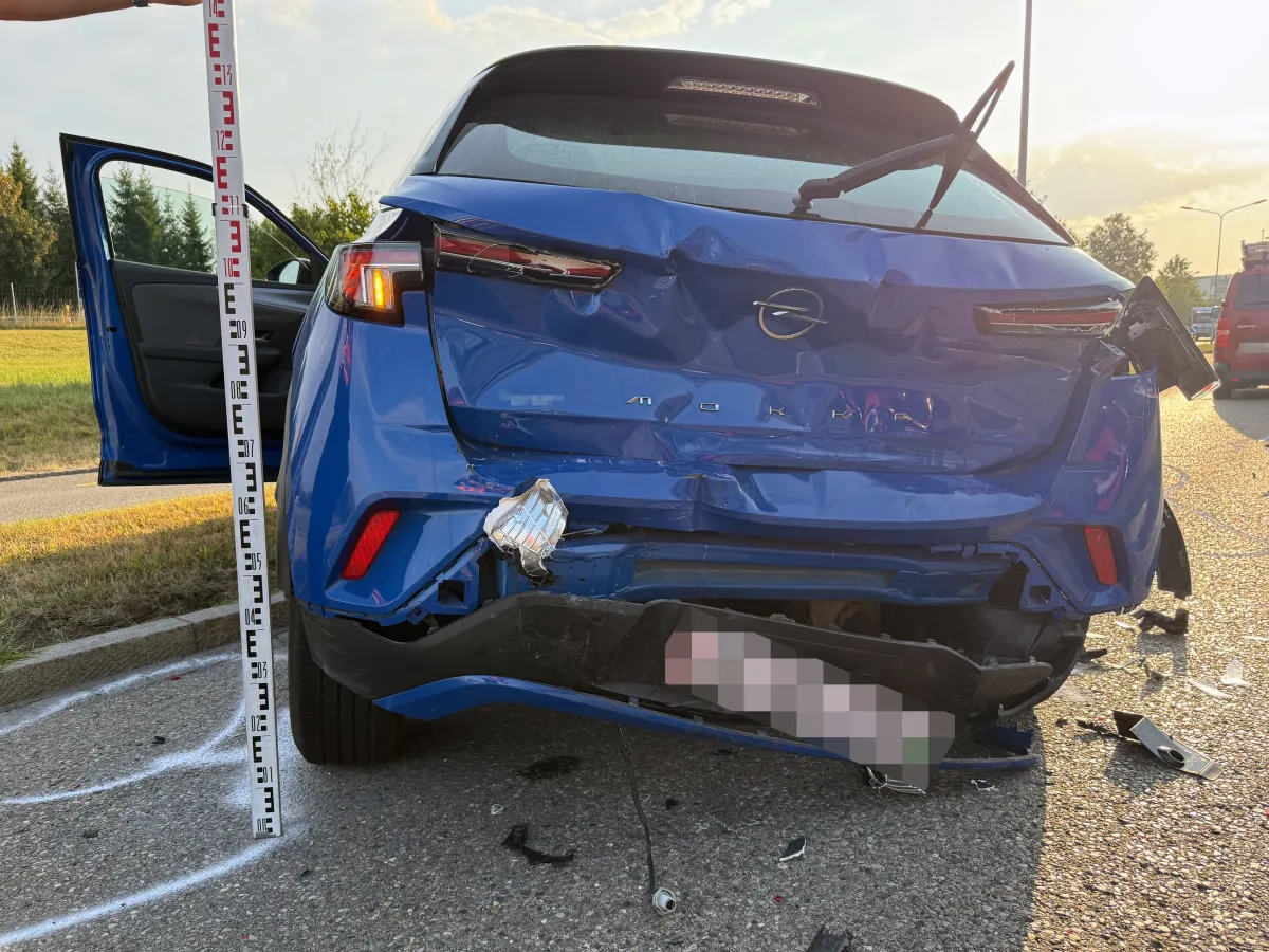 Ein blaues Opel-Auto zeigt schwere Schäden am Heck, mit einem auf den Boden gemalten Maßstab und verstreuten Trümmerteilen.