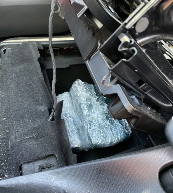 Ein geöffneter Autoteil zeigt in Plastik eingewickelte Pakete in einem versteckten Fach unter der Verkleidung.
