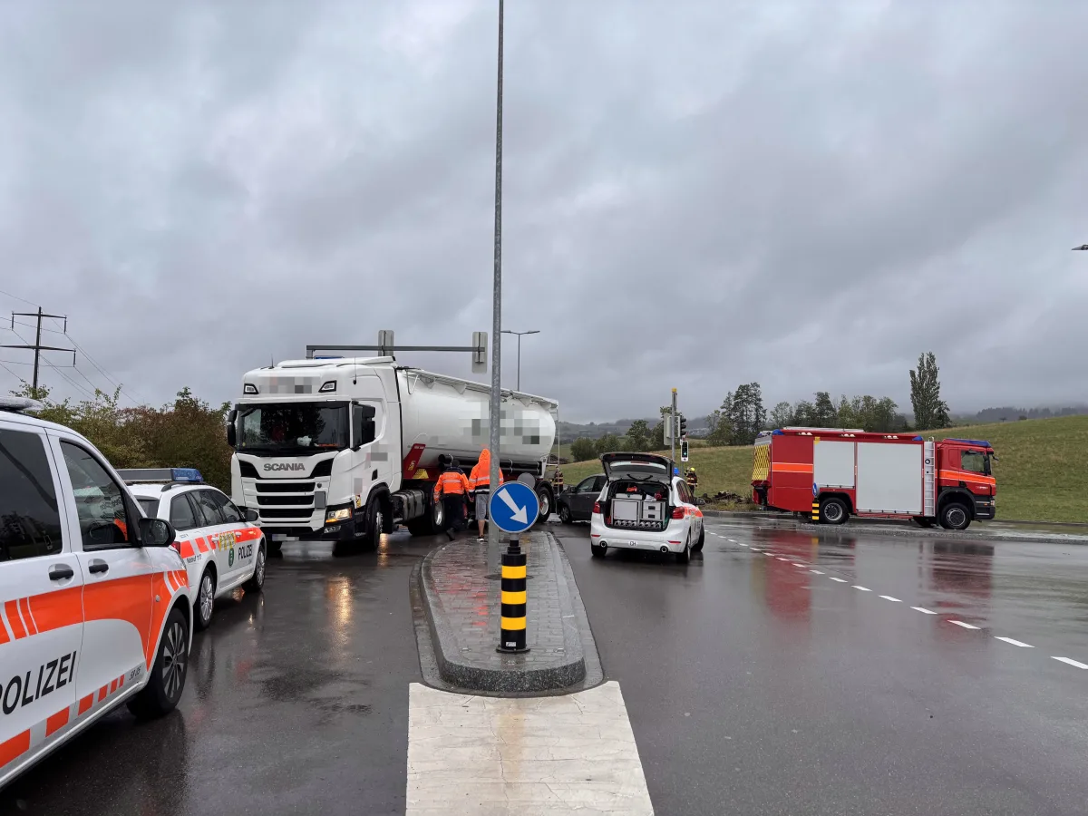 Mehrere Polizeifahrzeuge und ein großer Lastwagen stehen an einer Kreuzung. Ein rotes Feuerwehrfahrzeug ist ebenfalls vor Ort.