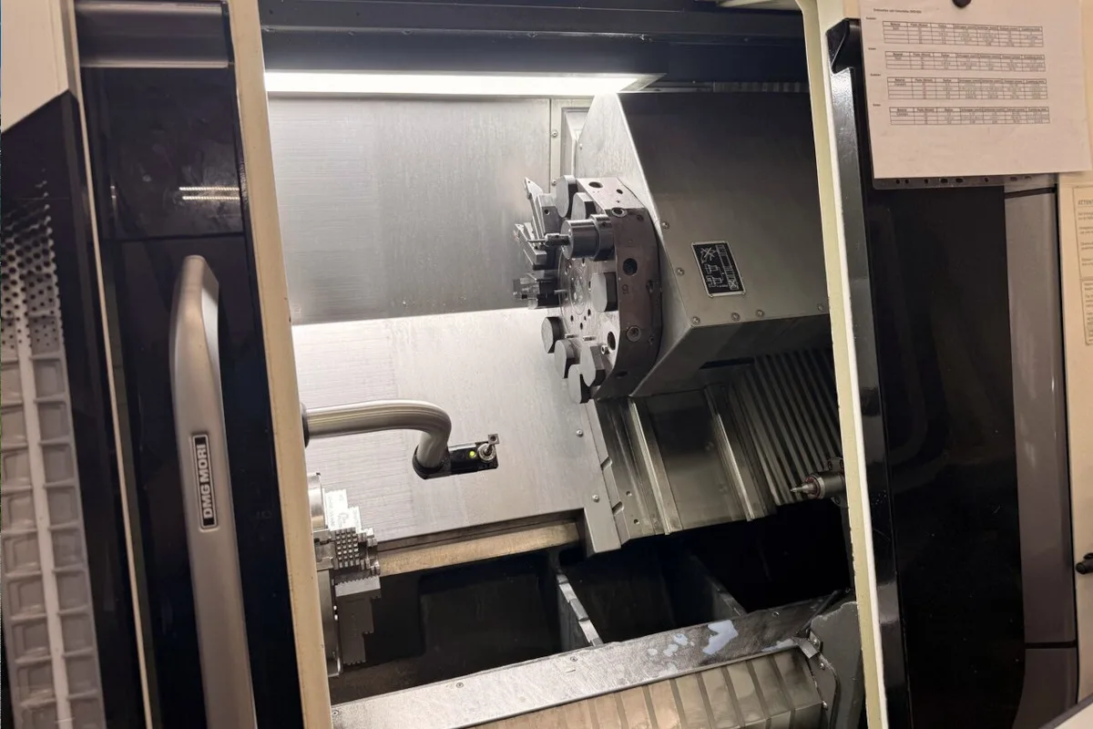 Eine CNC-Maschine in einem industriellen Raum ist zu sehen. Die Maschine scheint Teil eines Produktionsprozesses zu sein.