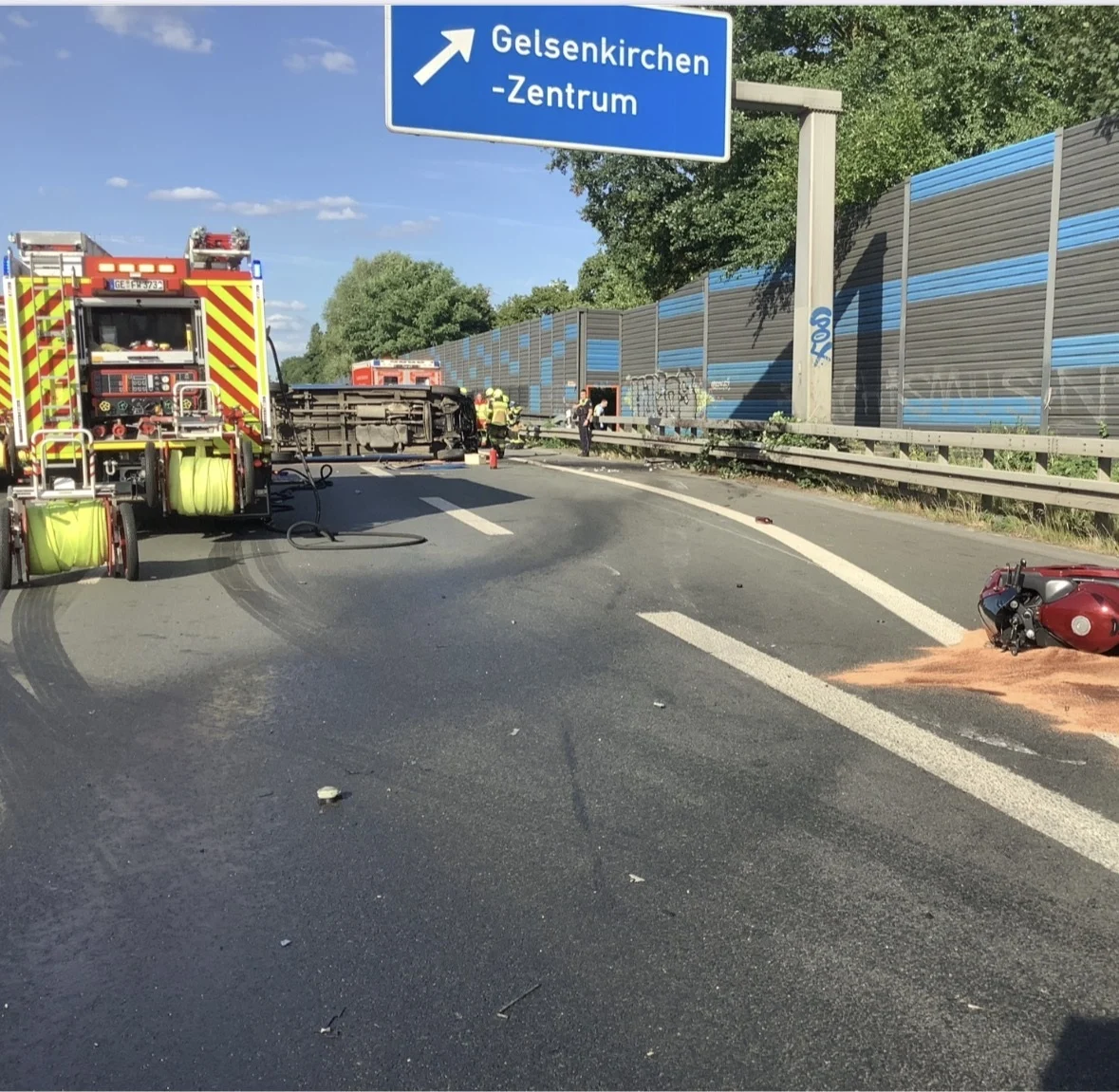 Ein umgekippter Transporter liegt auf einer Straße, umgeben von Feuerwehrfahrzeugen. Einsatzkräfte arbeiten an der Unfallstelle.
