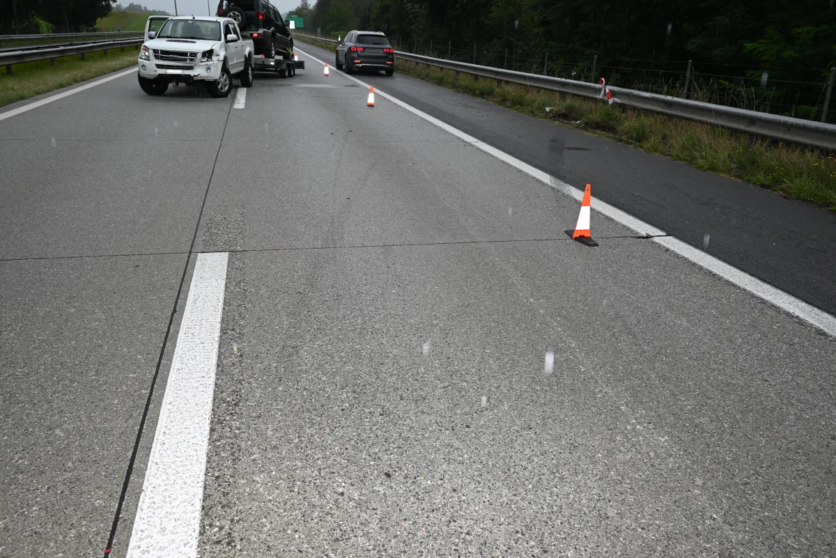 Ein beschädigtes weißes Auto steht auf einer Autobahn. Es sind Absperrkegel um das Fahrzeug platziert.