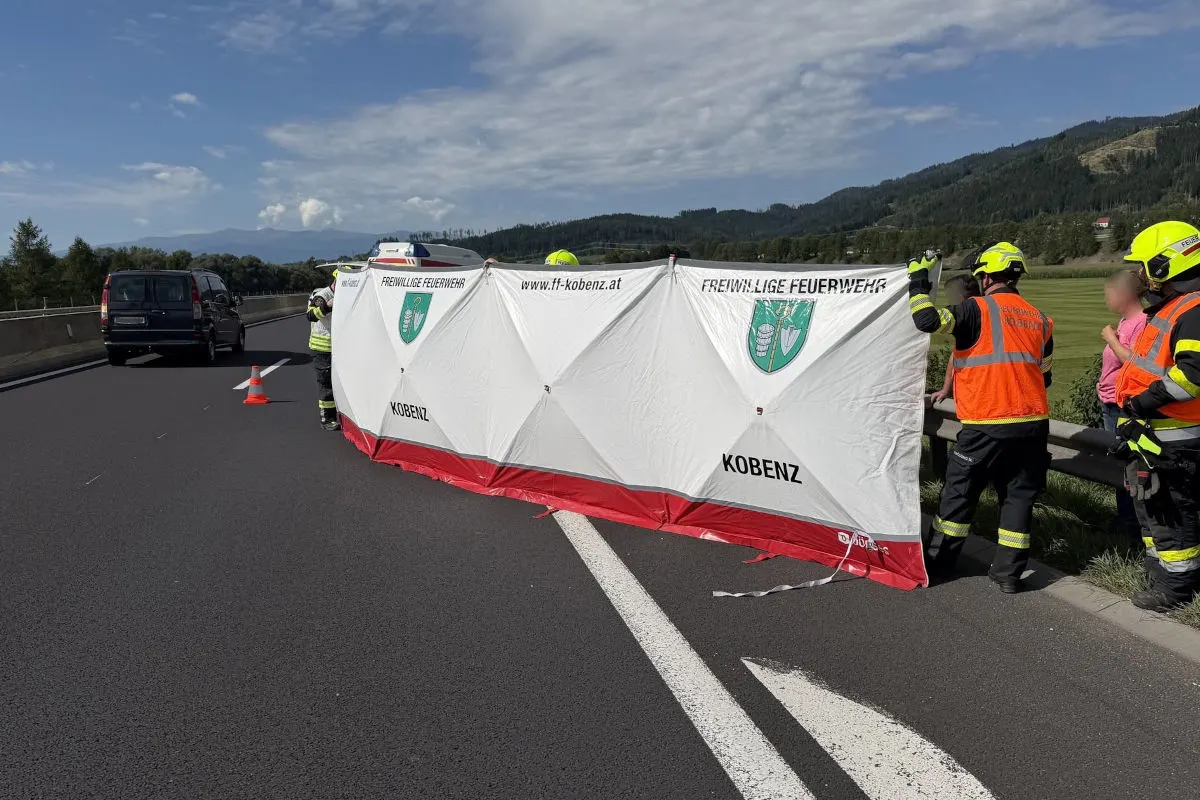 Feuerwehrleute der Freiwilligen Feuerwehr Kobenz stehen auf einer Autobahn und halten einen weißen Sichtschutz mit Vereinslogo.