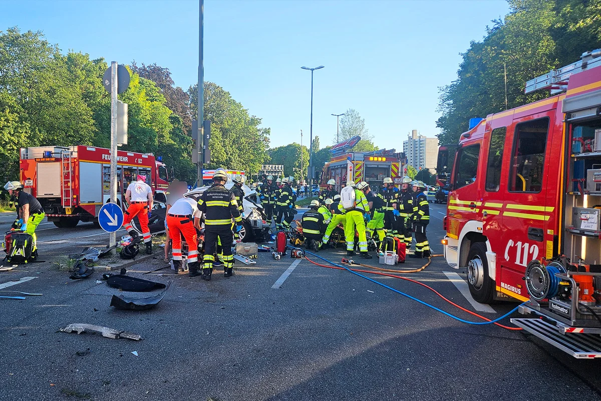 Mehrere Rettungskräfte versorgen Verletzte an einer Unfallstelle auf einer städtischen Straße, umgeben von Einsatzfahrzeugen.