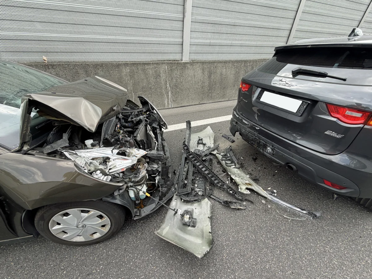 Die Front eines dunklen Autos ist stark beschädigt und in das Heck eines grauen Autos gefahren. Trümmer liegen auf der Straße.