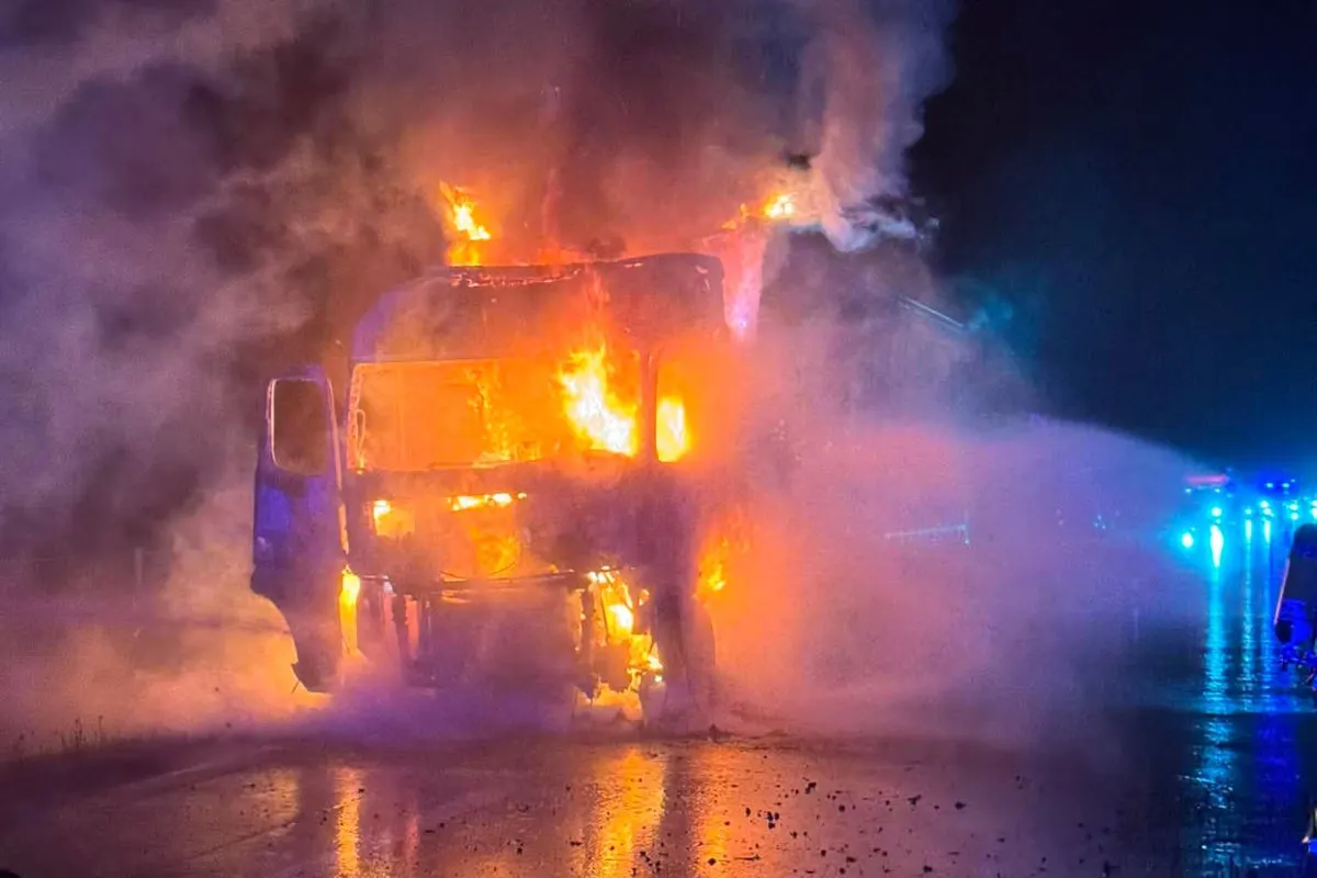 Ein Lastwagen brennt lichterloh auf einer Straße bei Nacht. Dichte Flammen und Rauch sind sichtbar.