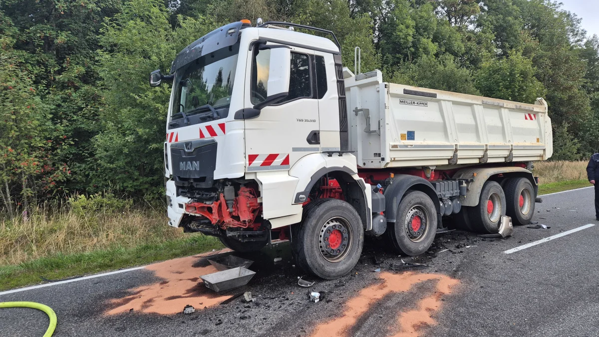 Ein MAN-Lastwagen mit sichtbaren Schäden steht am Straßenrand, umgeben von einer Ölspur und verstreutem Material.