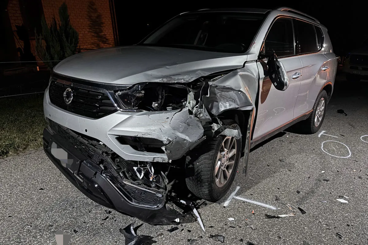 Ein silberner SUV mit erheblichen Schäden im Frontbereich steht auf einer Straße, umgeben von Trümmerteilen. Der Unfall ereignete sich bei Nacht.