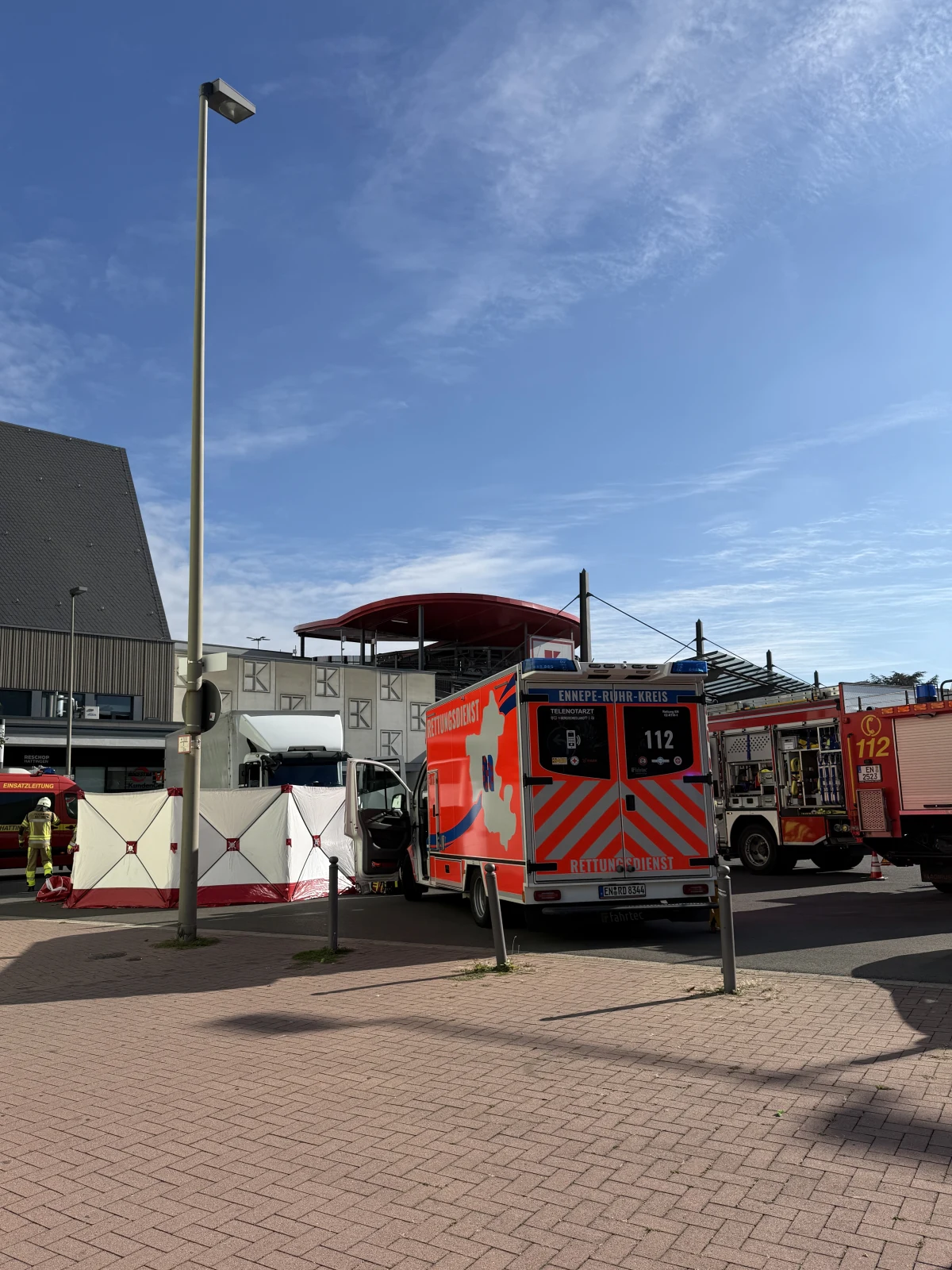 Ein Rettungsdienstfahrzeug des Ennepe-Ruhr-Kreises steht vor einer Absperrung. Feuerwehrfahrzeuge befinden sich im Hintergrund.