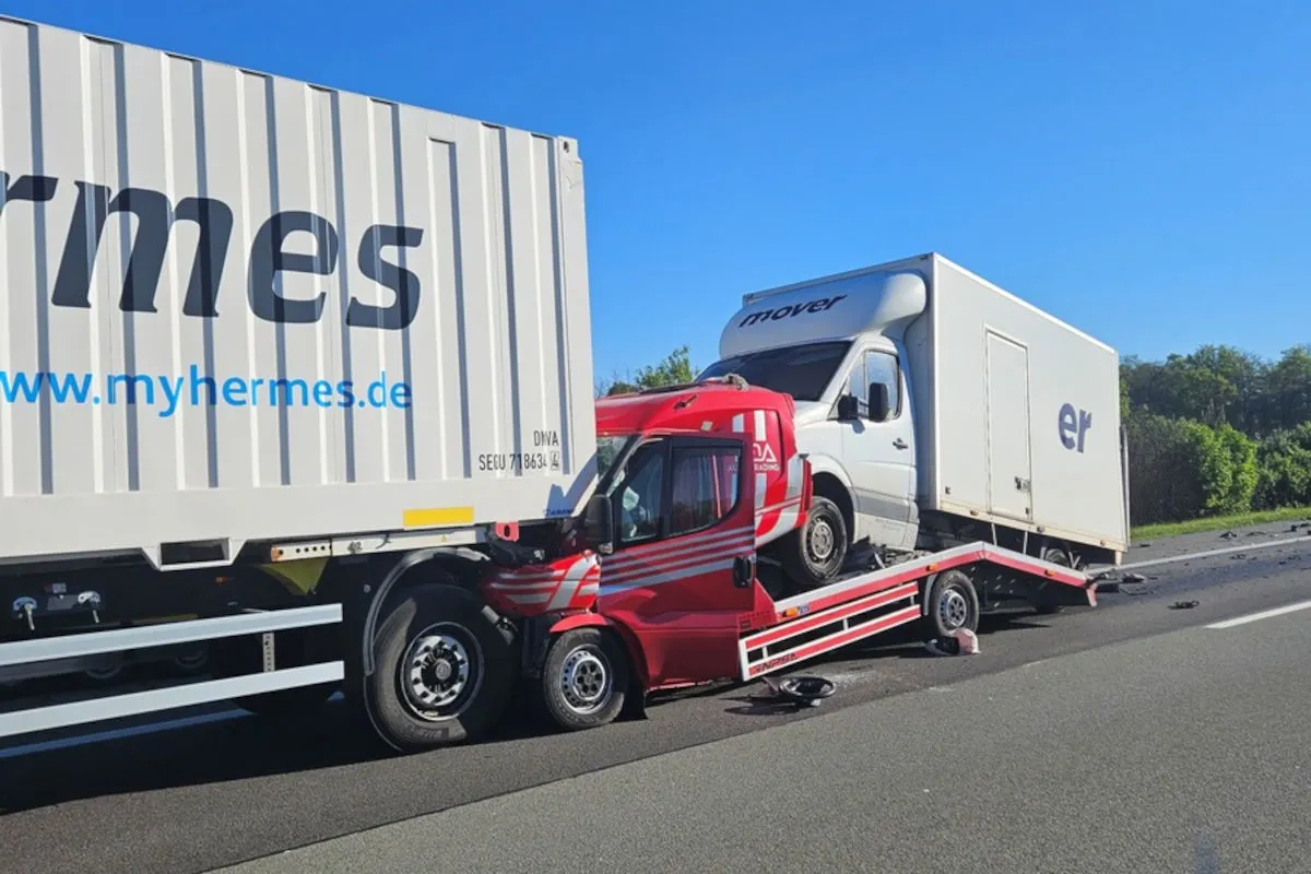 Ein rotes Transportfahrzeug ist unter einen weißen LKW gerutscht. Auf dem Transporter ist ein drittes Fahrzeug geladen.
