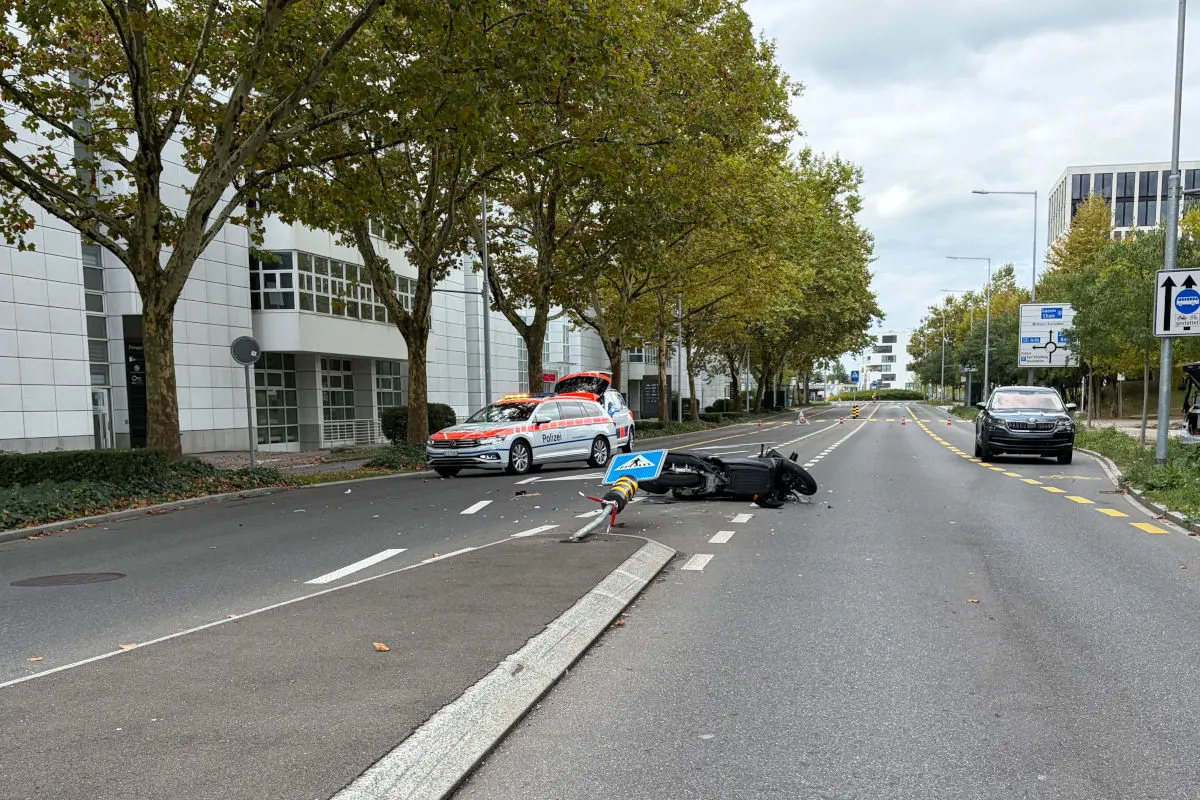 Ein Polizeiwagen steht mit geöffnetem Kofferraum auf einer Straße neben einem umgestürzten Motorrad und einem beschädigten Verkehrsschild.