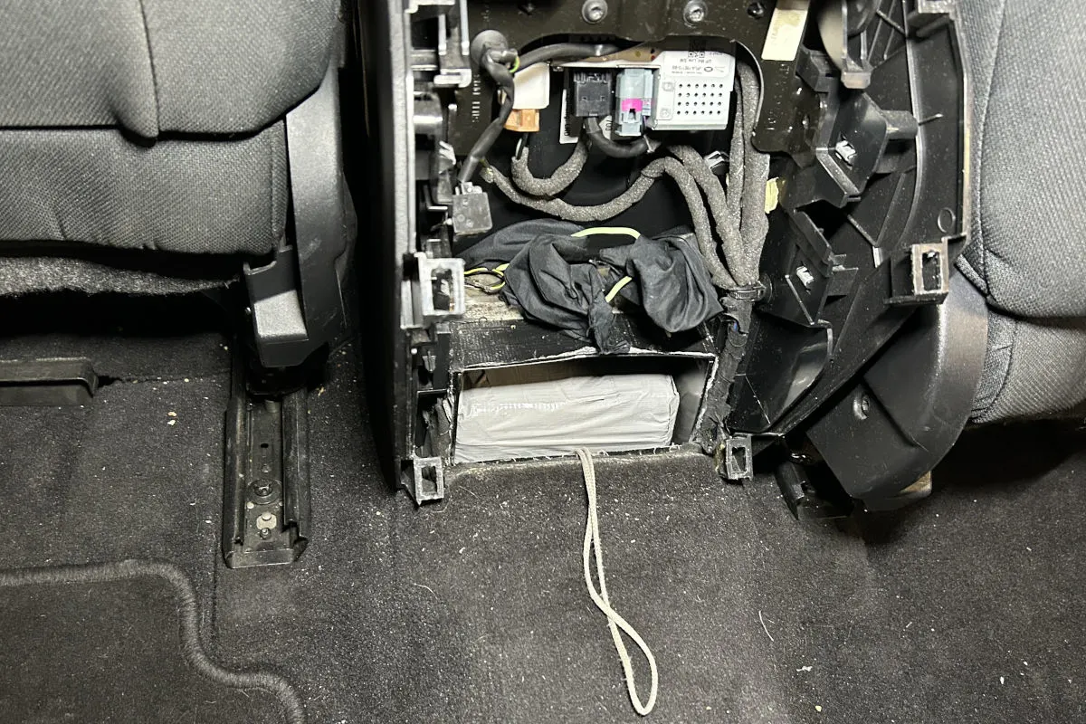 Ein offener Bereich im Inneren eines Autos zeigt Kabel und Raum, der als Versteck genutzt wurde. Im Inneren befindet sich ein Paket.