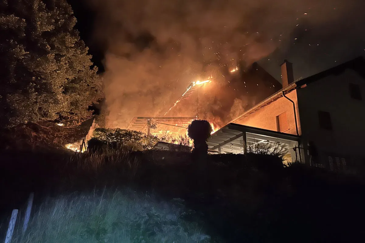 Ein Haus ist bei Nacht in Flammen gehüllt, mit starkem Feuerschein und Rauchentwicklung.