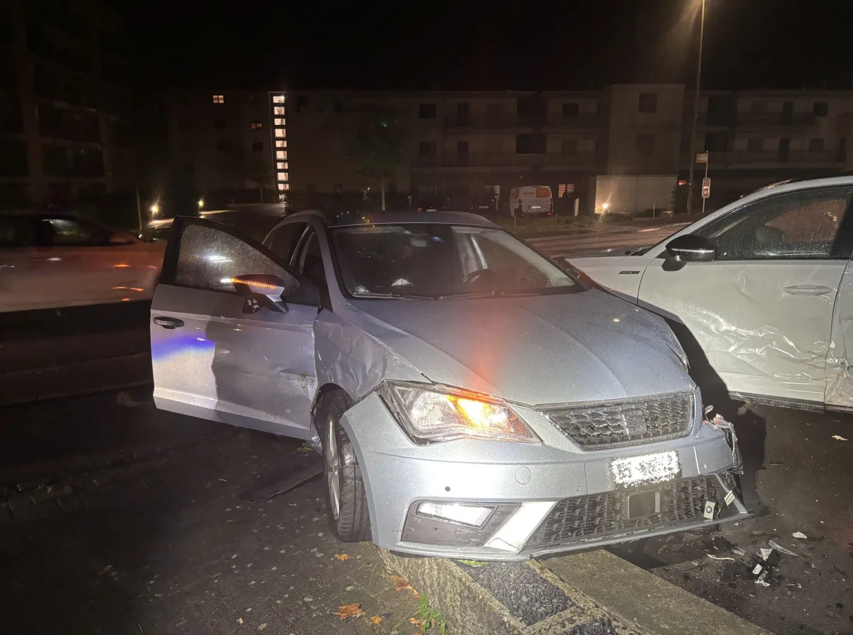 Ein silbernes Auto mit sichtbaren Schäden steht bei Nacht auf einer Straße. Ein anderes Fahrzeug ist ebenfalls betroffen.