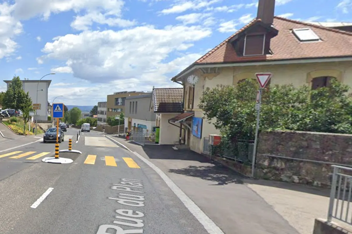 Ein Auto fährt auf einer Straße mit Zebrastreifen in einem Wohngebiet. Ein altes Gebäude im Hintergrund.