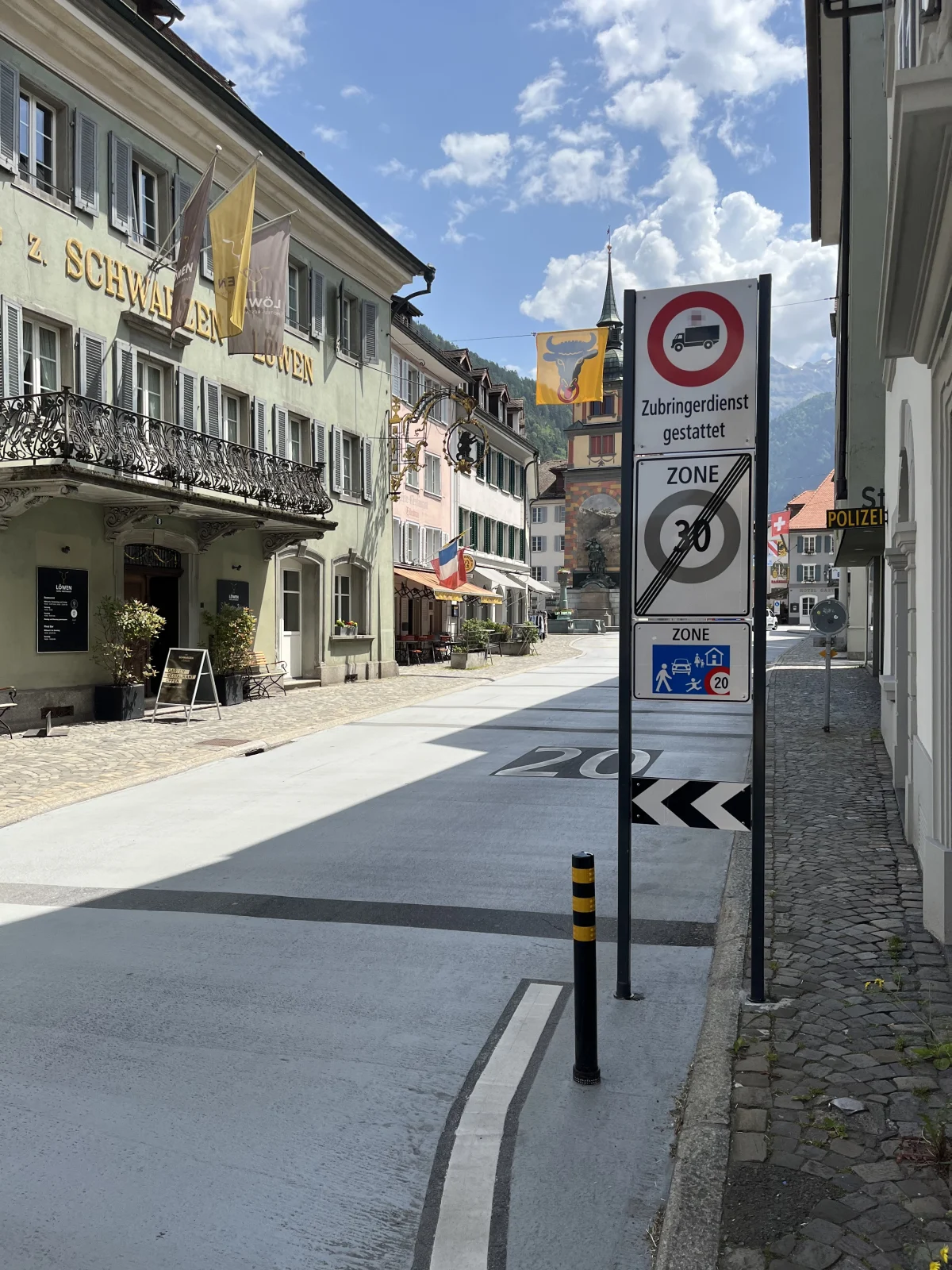 Eine schmale Straße in einer Altstadt mit mehreren Verkehrsschildern, die Geschwindigkeitslimits und Zufahrtsbeschränkungen anzeigen.