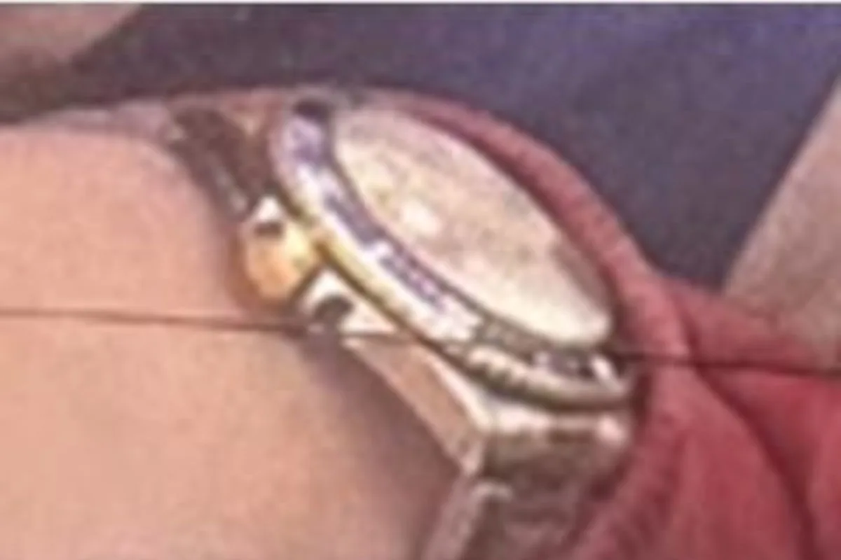 Eine Armbanduhr mit Metallarmband ist auf einem Handgelenk zu sehen. Der Hintergrund ist unscharf und nicht erkennbar.