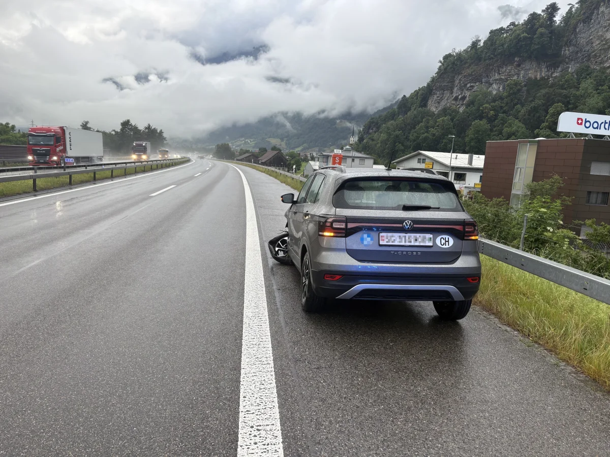 Auf einer regnerischen Autobahn steht ein grauer VW T-Cross auf dem Seitenstreifen. Im Hintergrund sind LKWs zu sehen.