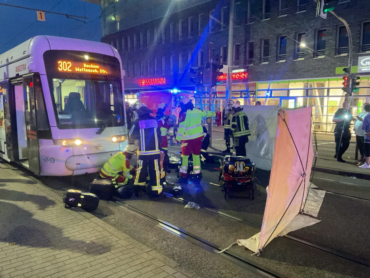 Eine Straßenbahn steht auf der Straße, umgeben von mehreren Rettungskräften. Ein Sichtschutz ist aufgestellt.