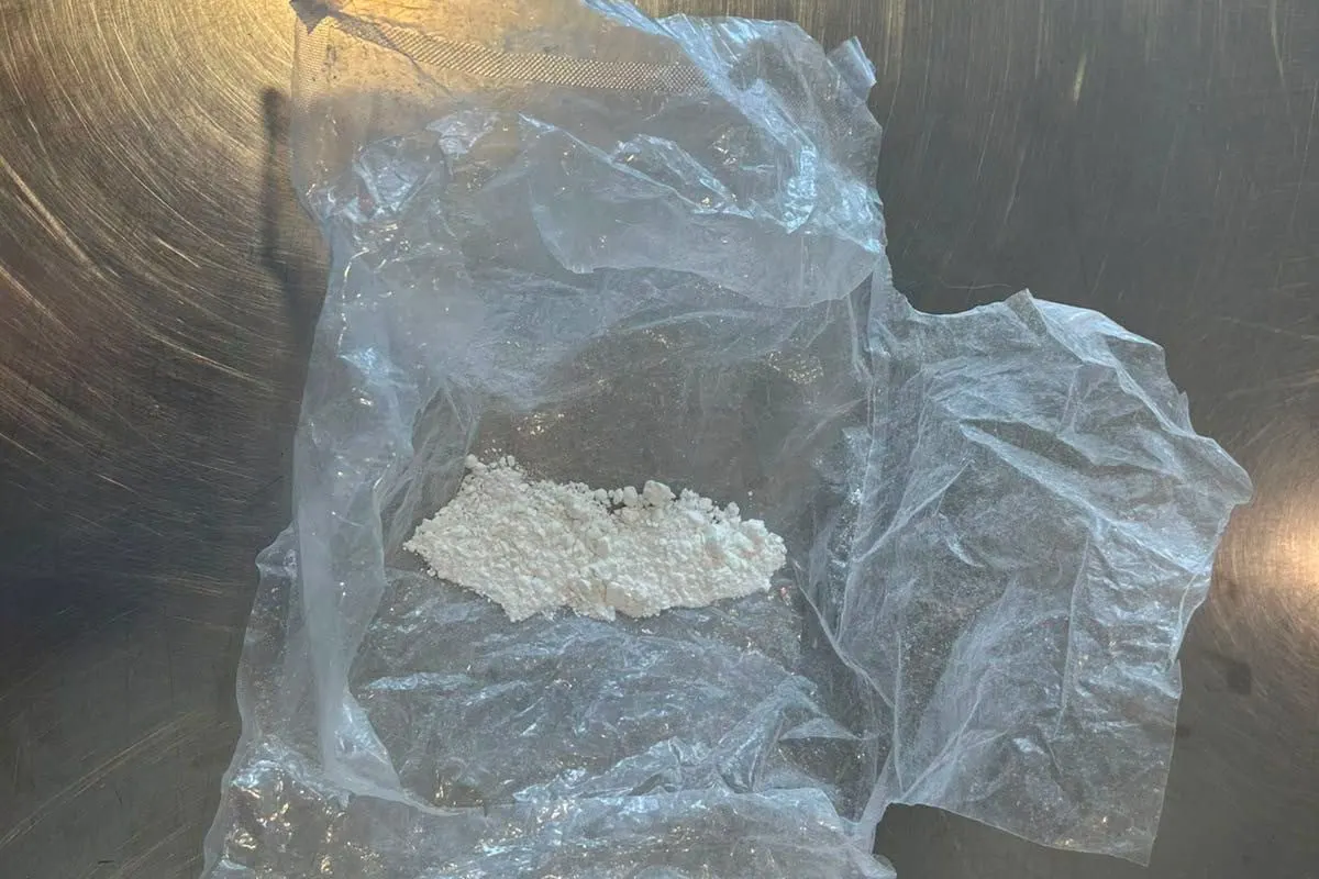 Ein transparenter Plastikbeutel mit weißem Pulver liegt auf einer Metalloberfläche. Das Pulver ist gut sichtbar im Beutel verteilt.