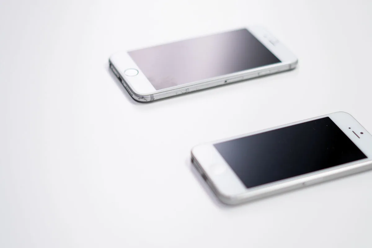 Zwei Smartphones mit schwarzen Bildschirmen liegen auf einer weißen Oberfläche. Beide Geräte sind abgeschaltet und nebeneinander platziert.