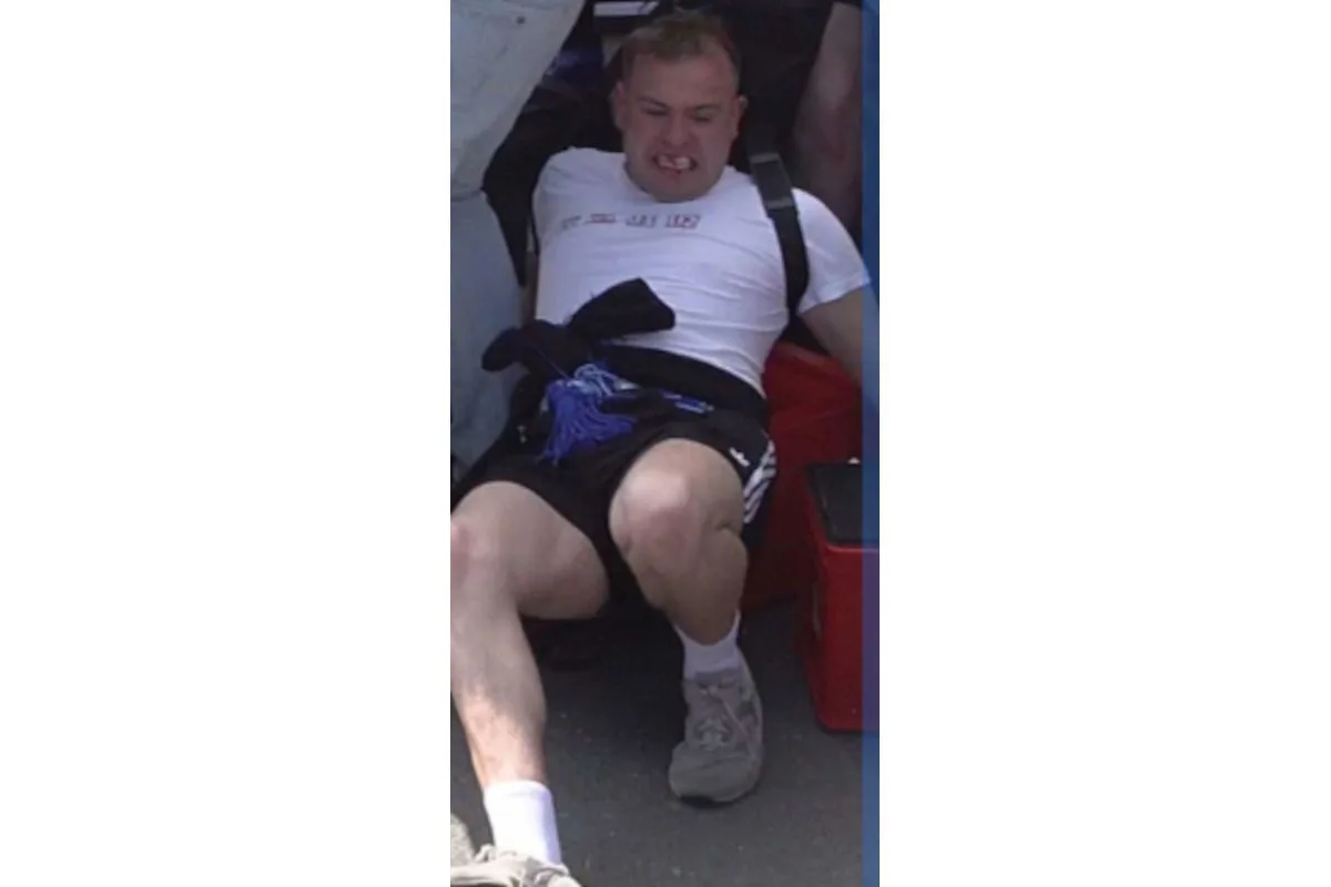 Ein Mann in Sportkleidung sitzt auf dem Boden und sieht erschöpft aus. Sein Gesichtsausdruck deutet auf starke Anstrengung hin.