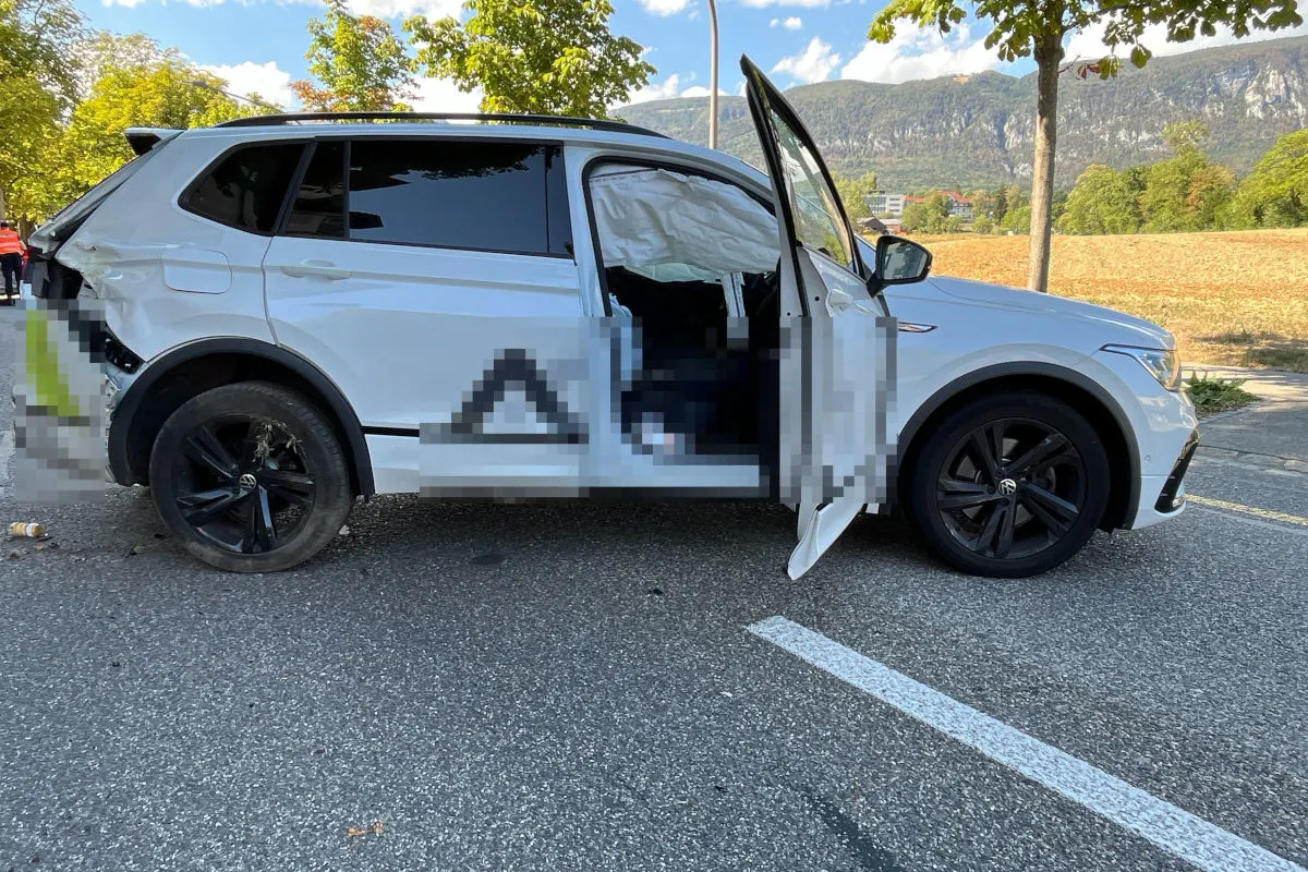 Ein weißer SUV mit sichtbaren Schäden steht auf einer Straße; die Airbags sind ausgelöst und die Türen sind geöffnet.