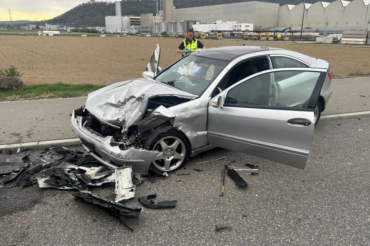 Ein silbernes Auto mit schweren Frontschäden steht am Straßenrand. Trümmerteile sind auf der Straße verstreut.