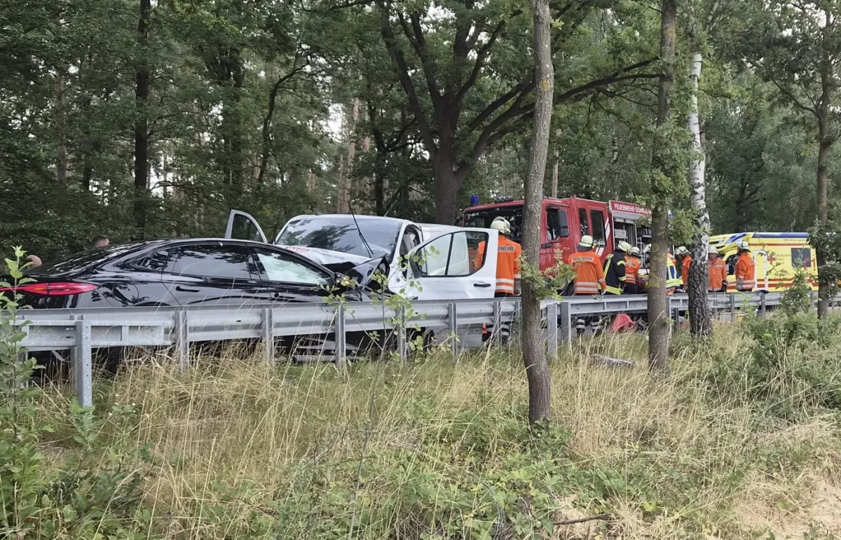 Mehrere Fahrzeuge sind auf einer Landstraße verunfallt, während Feuerwehrleute in orangenen Westen die Unfallstelle sichern.