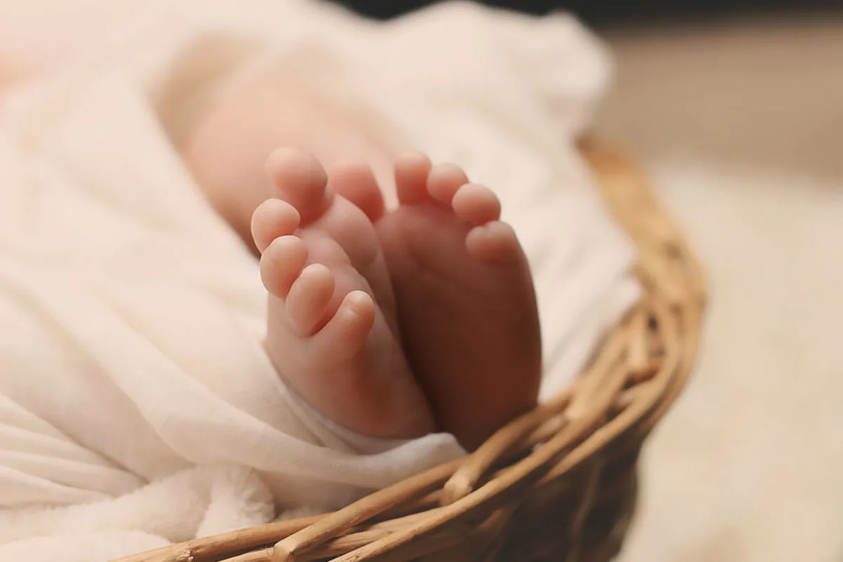 Die Aufnahme zeigt die Füße eines Babys, umhüllt von flauschigen weißen Decken in einem geflochtenen Korb.