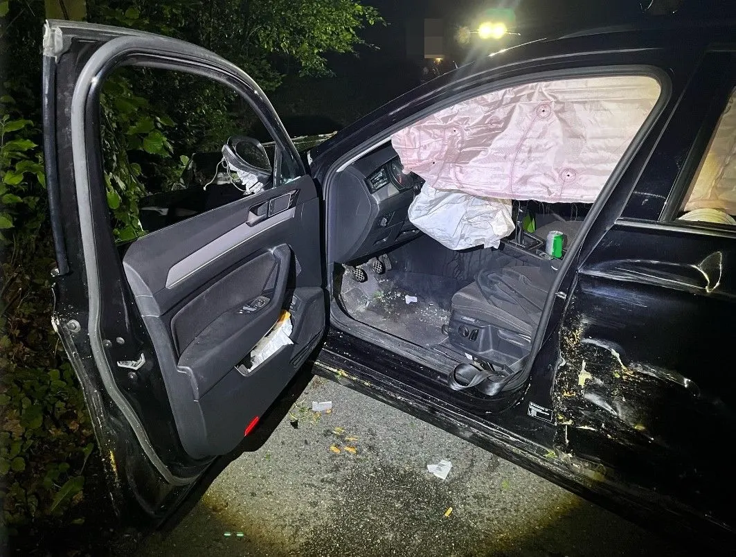 Zu sehen ist die geöffnete Fahrertür eines beschädigten Fahrzeugs mit ausgelösten Airbags. Es befinden sich keine Personen im Auto, und die Szene findet nachts statt.