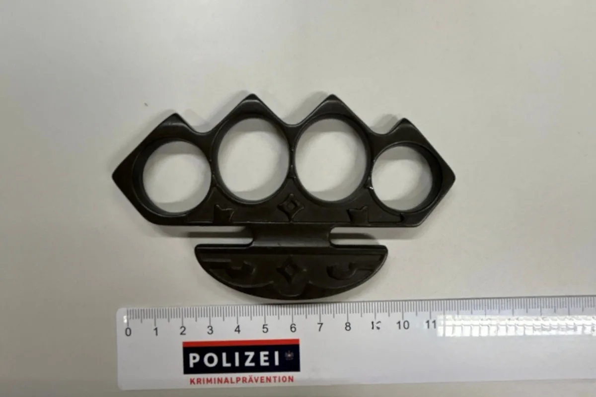 Ein Schlagring, der potenziell als Waffe verwendet werden kann, liegt auf einem Tisch neben einem Lineal mit der Aufschrift 'Polizei Kriminalprävention'.