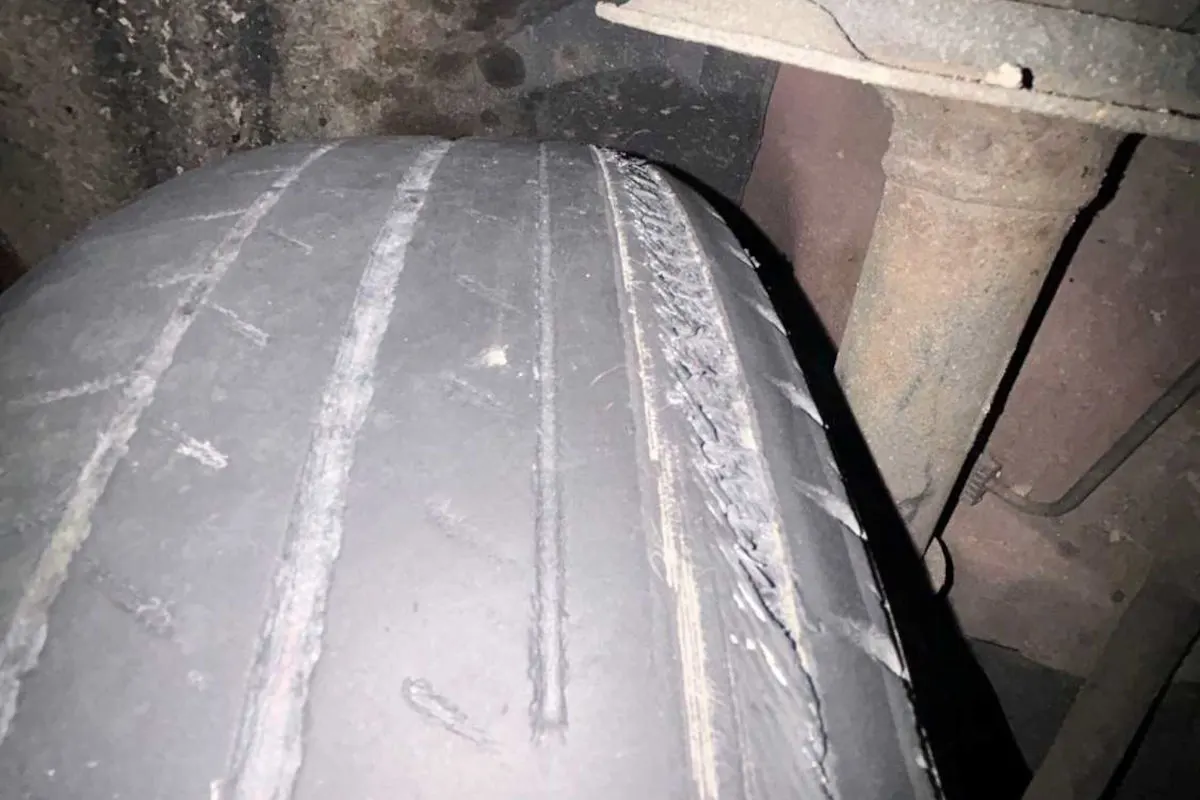 Das Bild zeigt einen stark abgenutzten Autoreifen mit sichtbaren Schäden. Der Reifen ist fast profillos und zeigt Risse.