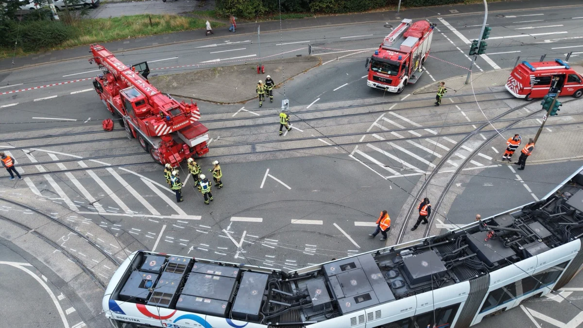 Eine entgleiste Straßenbahn liegt auf den Schienen an einer Kreuzung, umgeben von Feuerwehrfahrzeugen und Einsatzkräften.