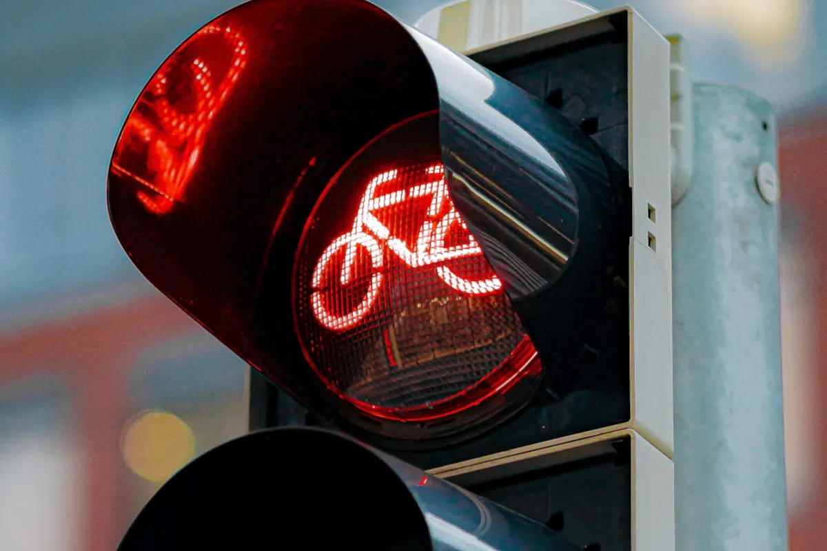 Eine Nahaufnahme einer roten Fahrradampel mit einem leuchtenden Fahrradsymbol. Die Ampel signalisiert 'Stopp' für Radfahrer im städtischen Umfeld.