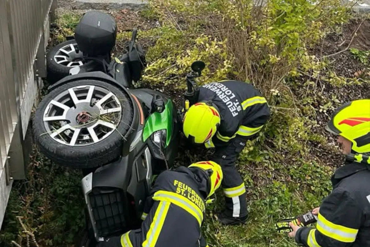 Ein umgestürztes Motorrad liegt im Gebüsch, umgeben von zwei Feuerwehrleuten in Schutzkleidung aus St. Lorenzen.