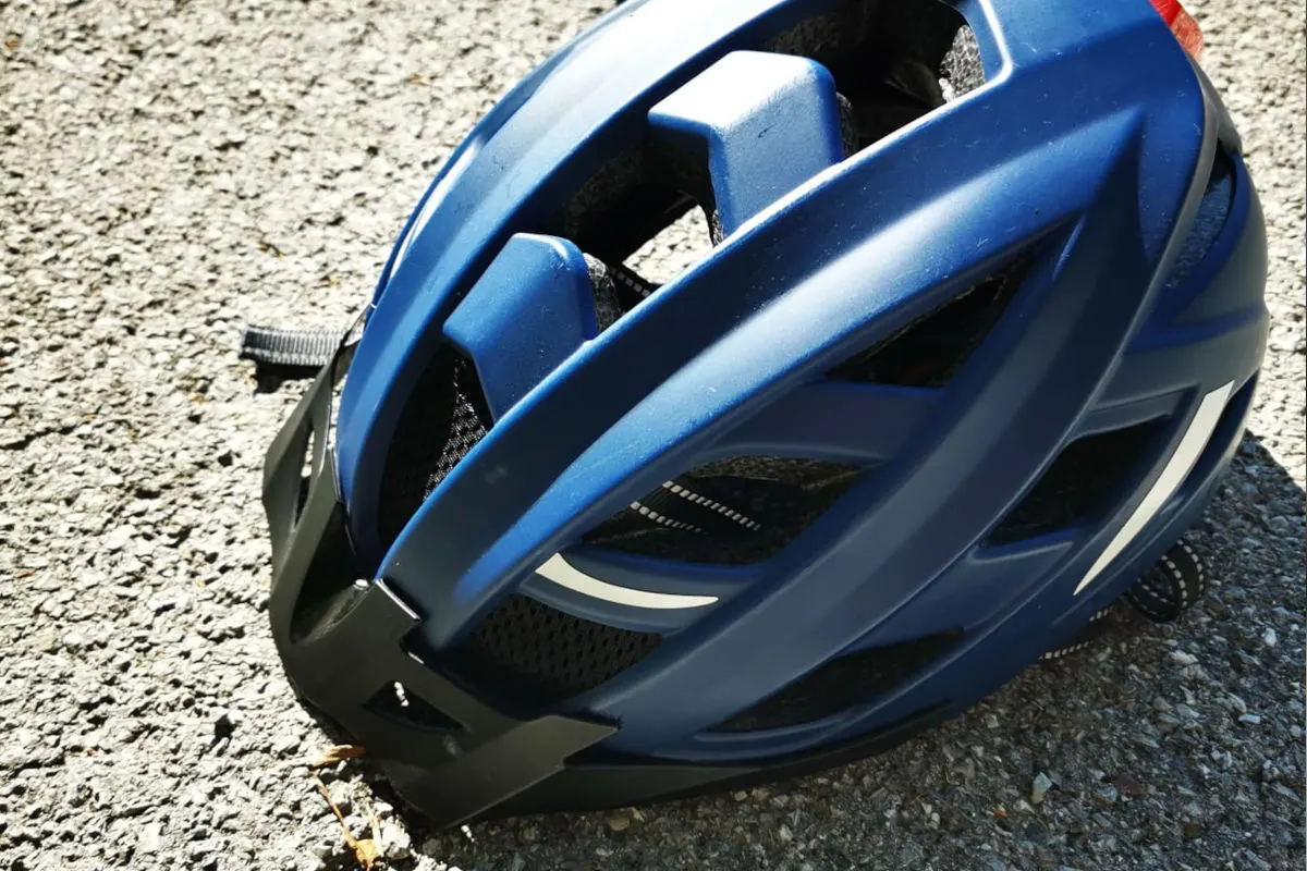 Ein blauer Fahrradhelm liegt auf dem Asphalt, möglicherweise involviert in einen Unfall oder Vorfall.