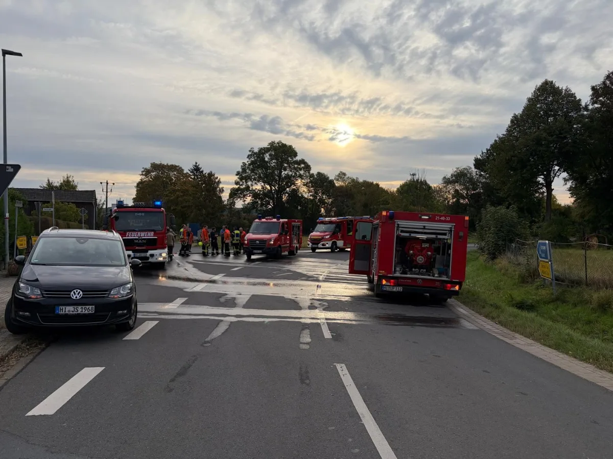 Drei Feuerwehrfahrzeuge stehen auf einer Landstraße. Feuerwehrleute sind vor Ort, während ein VW am Straßenrand geparkt ist.