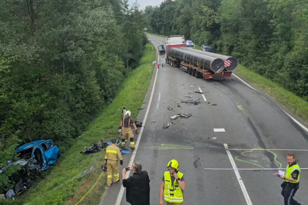 Ein Lkw steht quer auf der Straße, ein beschädigter blauer Pkw liegt im Graben. Feuerwehr und Personen sind vor Ort.