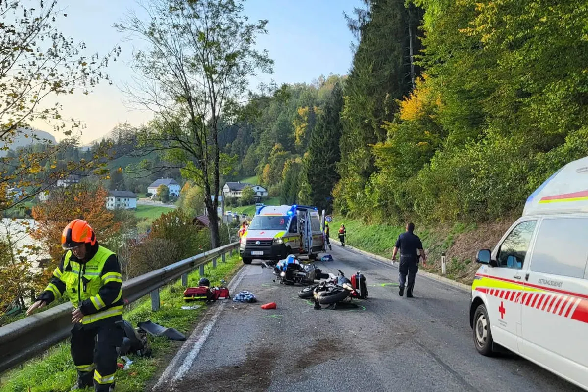 Auf einer Landstraße sind zwei beschädigte Motorräder zu sehen. Rettungsdienstfahrzeuge stehen daneben, und Rettungskräfte arbeiten an der Unfallstelle.