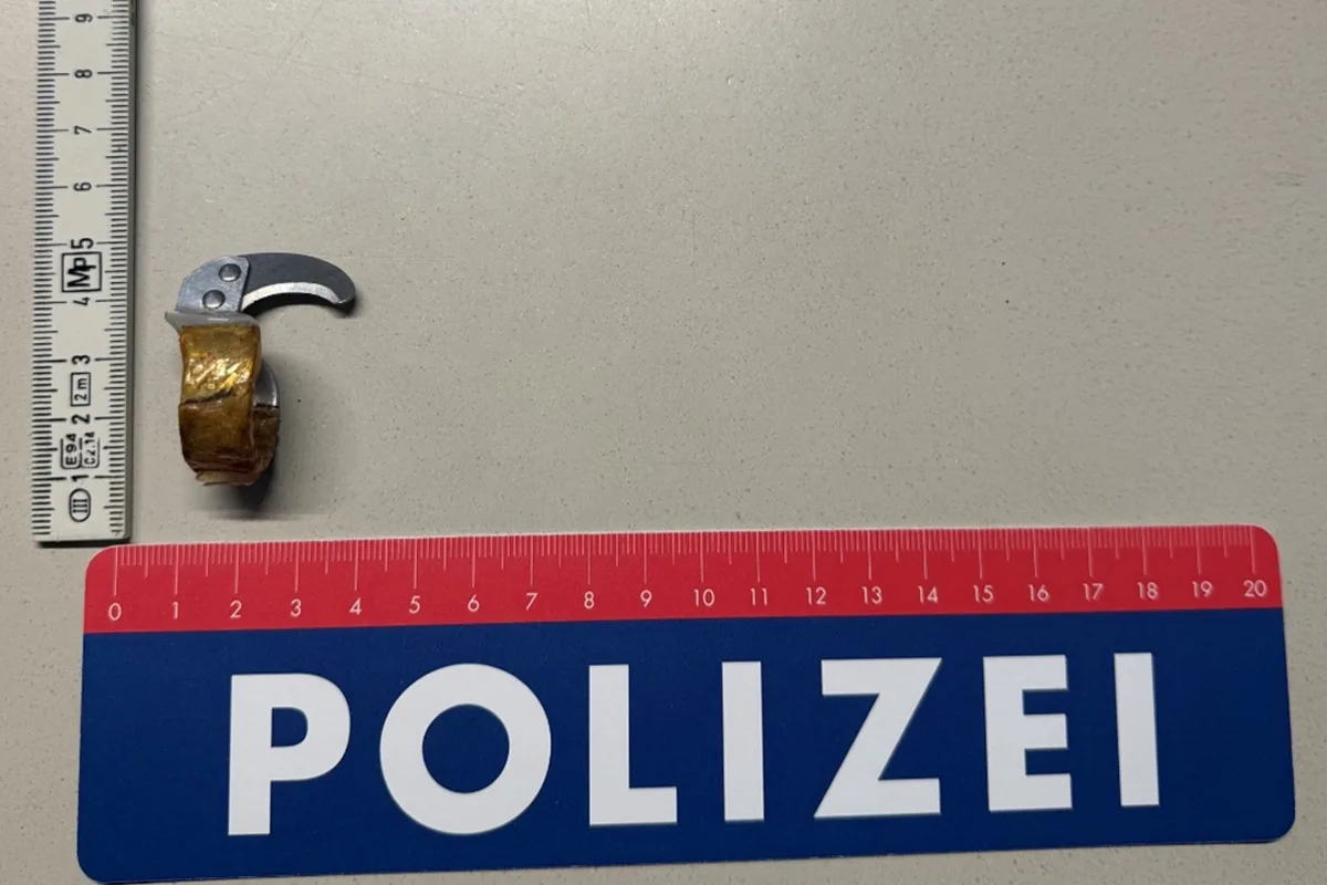 Auf einem Tisch liegt ein metallener Gegenstand mit einer Klinge, platziert neben einem Lineal und einem Polizei-Messstab.