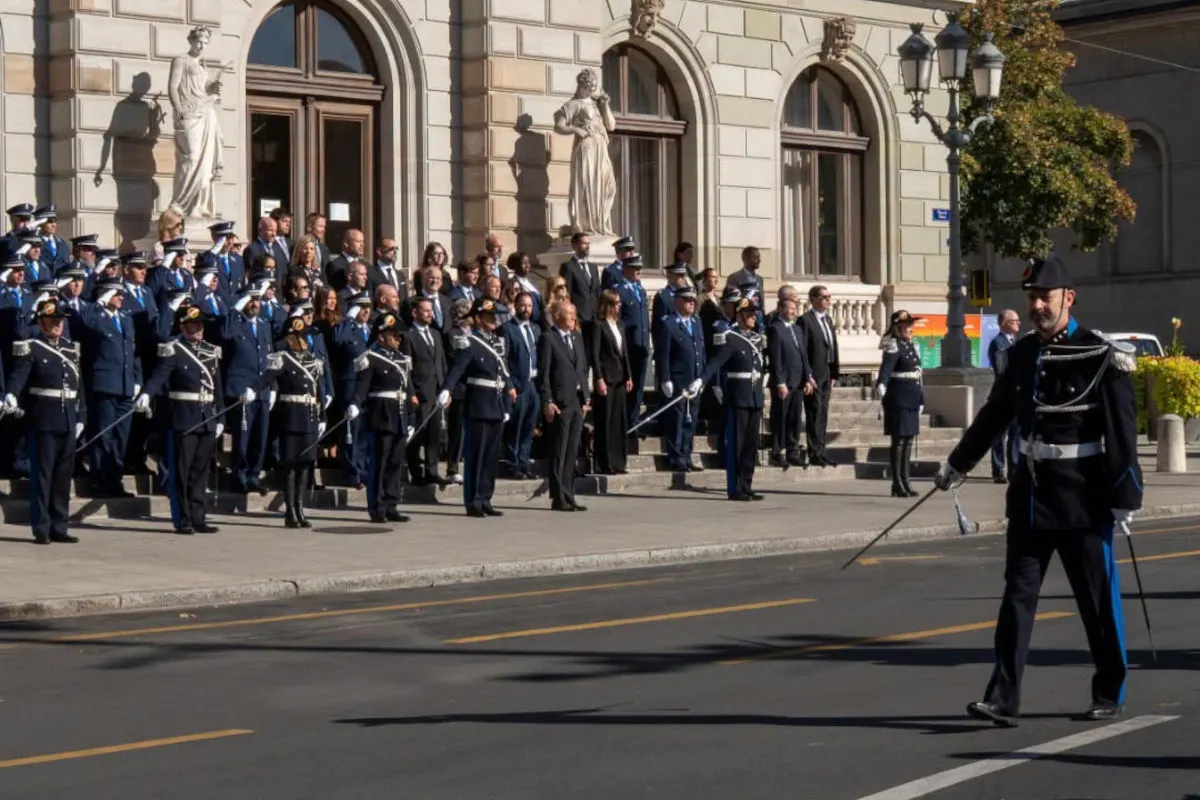 Mehrere Polizisten und Zivilpersonen stehen vor einem historischen Gebäude. Einer der Polizisten trägt eine Paradeuniform und marschiert mit einem Schwert.