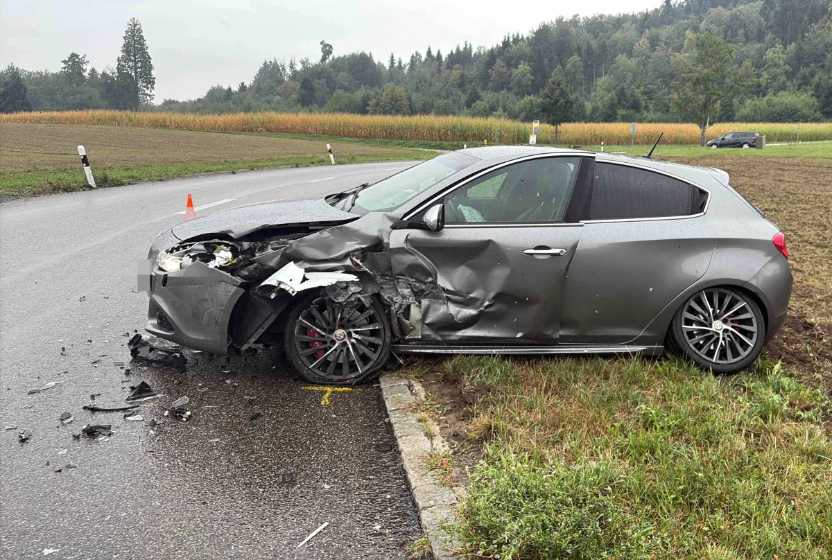 Ein silbernes Auto steht mit schwerem Front- und Seitenschaden am Straßenrand. Teile liegen auf der Straße.