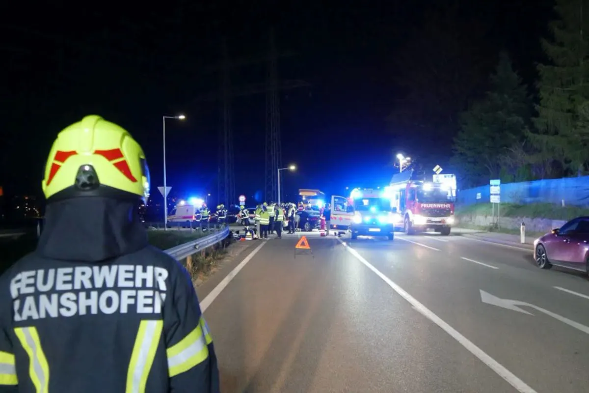 Auf einer nächtlichen Straße sind Feuerwehr- und Rettungskräfte vor Ort. Mehrere Einsatzfahrzeuge stehen mit aktivierten Blaulichtern auf der Fahrbahn.