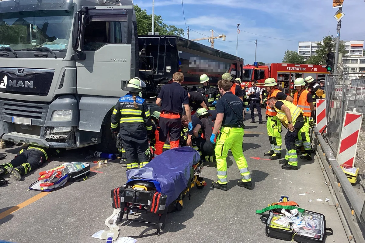 Mehrere Feuerwehrleute und Rettungskräfte arbeiten neben einem grauen Lkw, auf dem Boden liegt medizinisches Equipment.